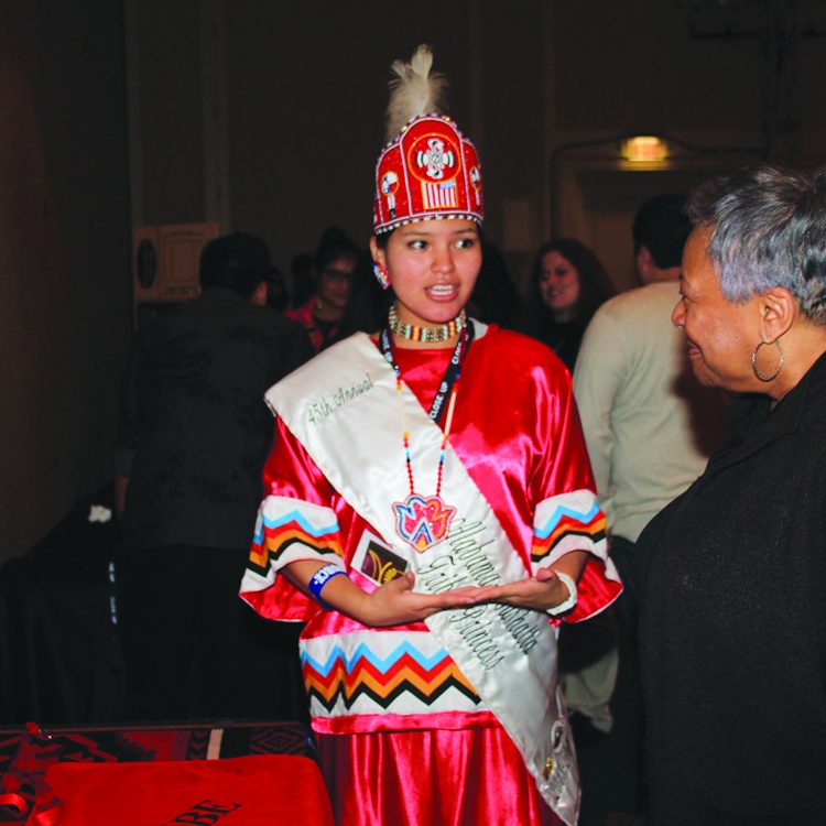 American Indian female student presenting in red tribal clothing on American Indian program