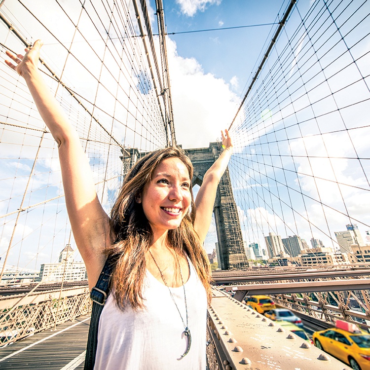 High school female student exploring New York City on Brooklyn Bridge